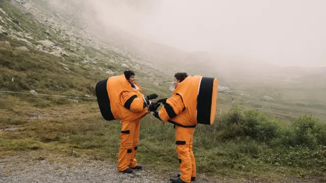 Dos personas con trajes naranjas de astronauta en los Alpes suizos. 