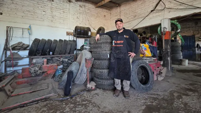 Un gomero en un taller mecánico rodeado de llantas. 