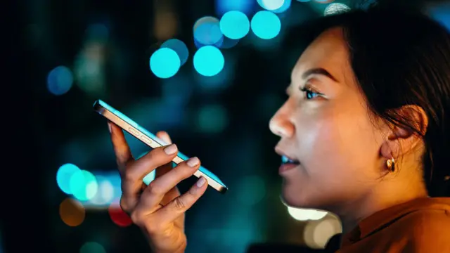Una joven mujer asiática envía un mensaje de voz por teléfono