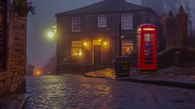 Un bar de Haworth en la noche, junto a uno de los tradicionales buzones de correo ingleses rojos.