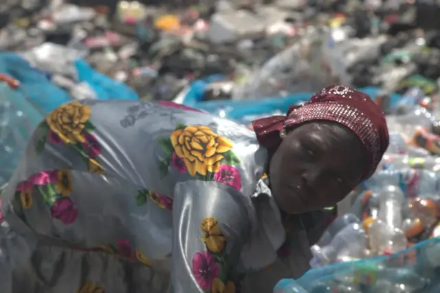 Una mujer recoge botellas plásticas