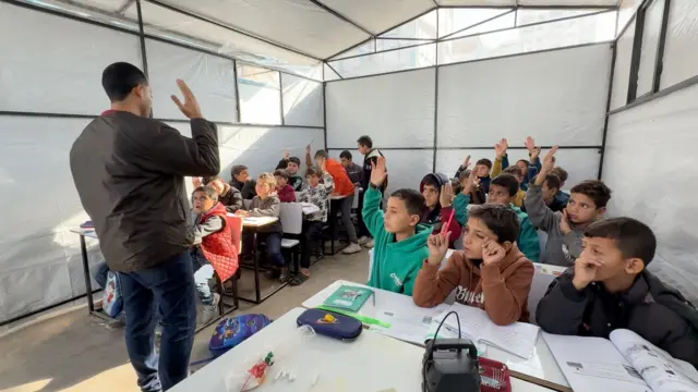 Niños en un aula creada en una tienda de campaña en Gaza.