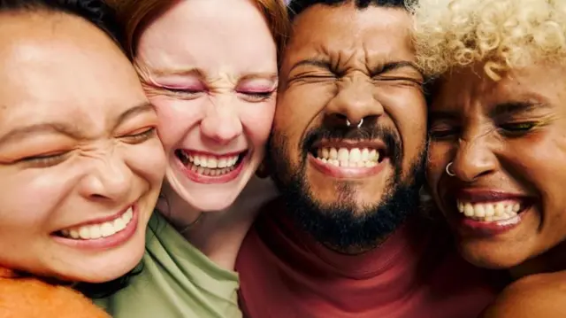 Las caras de tres mujeres y un hombre sonrientes