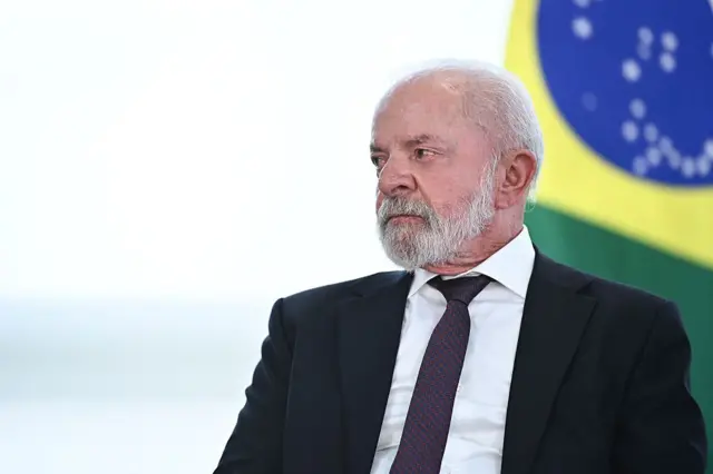 Retrato del presidente Lula sentado y detrás de él una bandera de Brasil