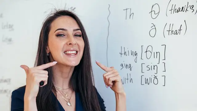 Profesora de inglés enseñando cómo colocar la lengua entre los dientes para realizar un sonido específico