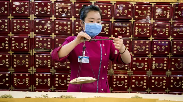 Una mujer pesa productos en una farmacia de medicina tradicional china.