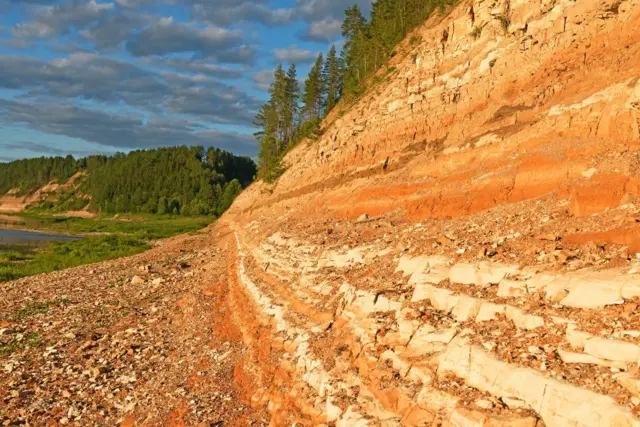 Capas de piedra arcillosa pérmica de rayas multicolores en las orillas del río Sukhona.