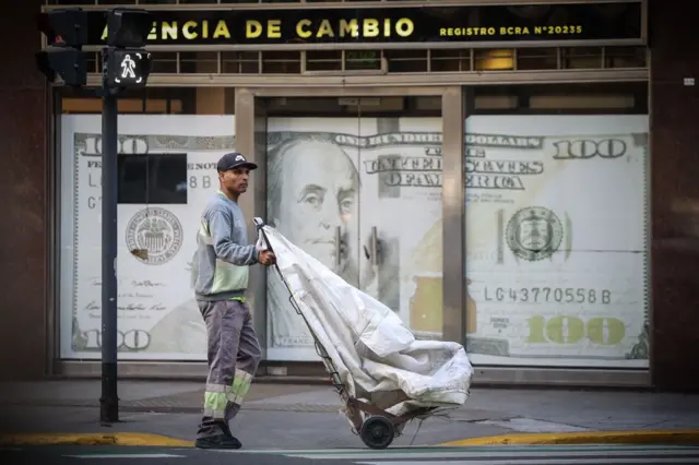 Hombre delante de un afiche de un billete de 100 dólares en Buenos Aires