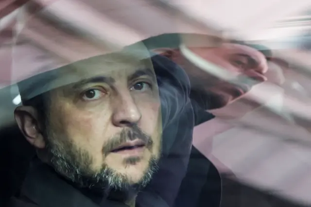 El reflejo de un agente de seguridad aparece en la ventanilla de un coche mientras el presidente de Ucrania, Volodymyr Zelenskiy, está sentado dentro.