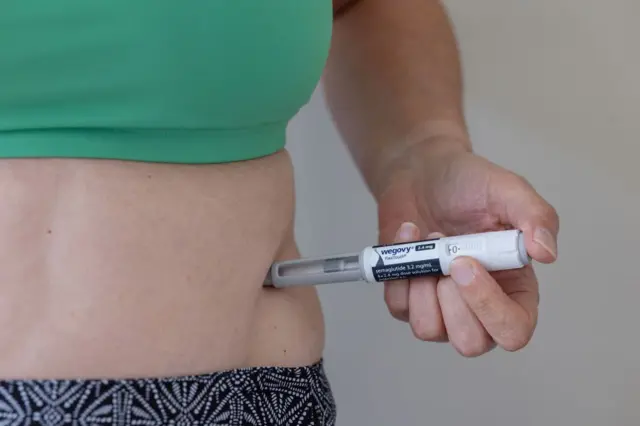 Persona aplicándose Wegovy en el abdomen.