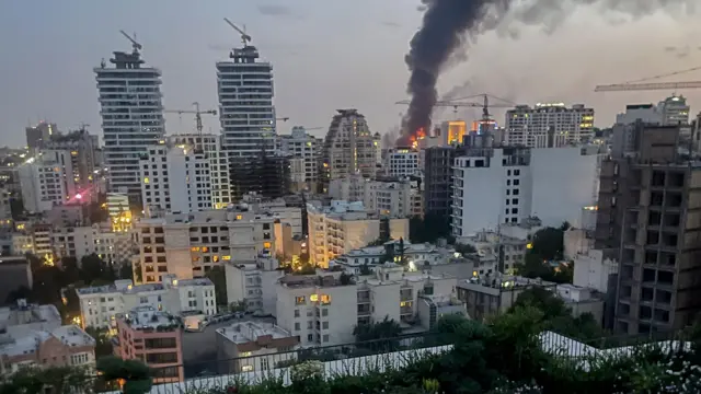 Sobre el cielo nocturno de Teherán se eleva humo procedente de los escombros del edificio de los medios de comunicación estatales iraníes tras un ataque aéreo israelí.