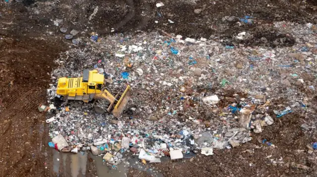 Una excavadora remueve desperdidicios en el vertedero. 