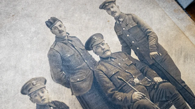 Una foto en sepia de un grupo de cuatro hombres con uniforme militar.
