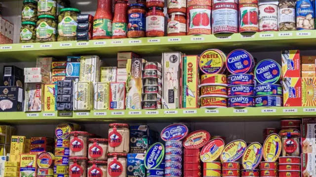 Estantería en un supermercado con decenas de latas de comida de todos los colores.