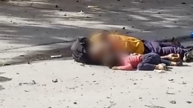 Una imagen fija de un vídeo muestra a un hombre con una camiseta amarilla tumbado en la calle junto a un niño pequeño que lleva una camiseta rosa. Las cabezas de ambos aparecen difuminadas.