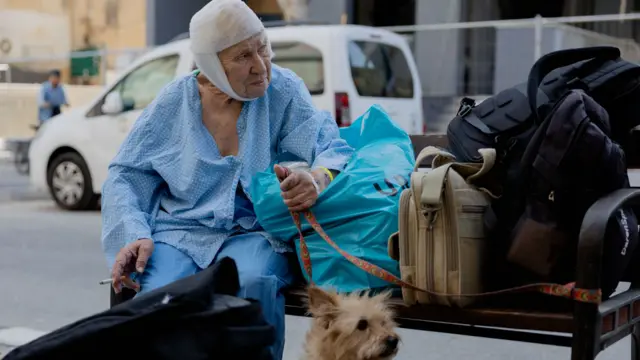 Una anciana herida con sus pertenencias.