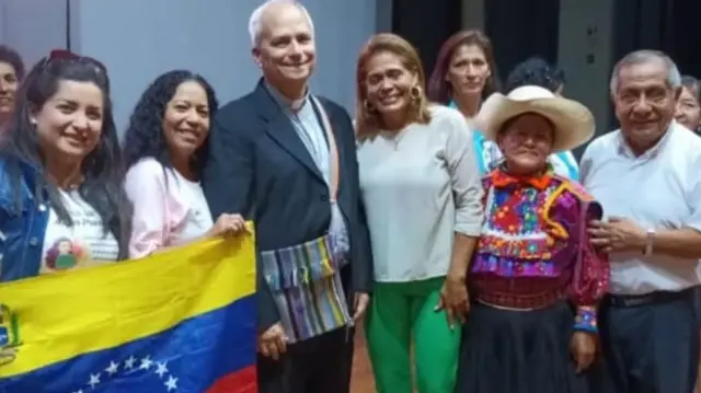 Lizbeth Díaz, junto al entonces obispor Robert Prevost y una bandera venezolana.