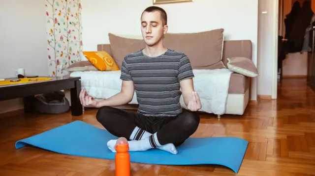 Joven sentado en un mat de yoga, meditando.