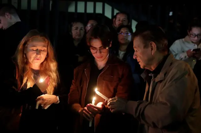 Personas encienden velas para rendir homenaje