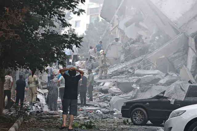 Gente observa los daños en los edificios de la plaza Nobonyad tras los ataques aéreos israelíes el 13 de junio de 2025 en Teherán, Irán.