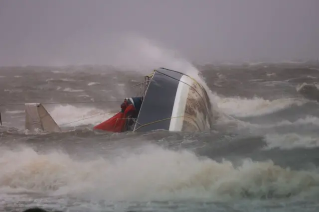 Una embarcación volcada llega a tierra mientras el huracán Helene se agita mar adentro.