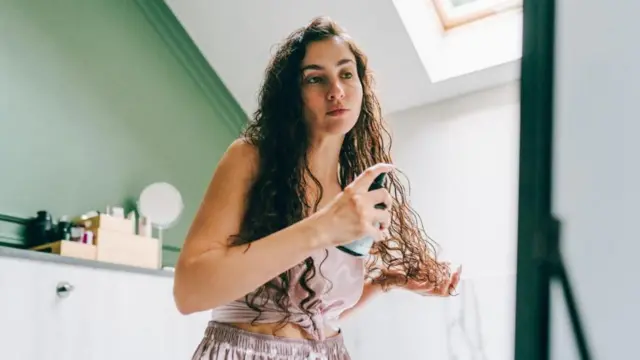 Mujer aplicándose un producto en las puntas del cabello