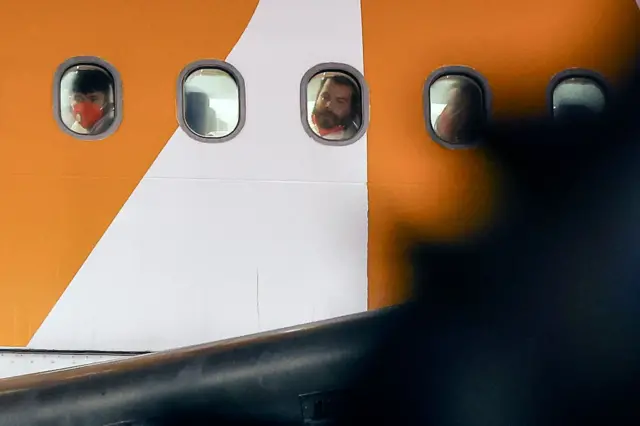 Personas miran por la ventana en el vuelo que llevò a 261 personas a El Salvador de EE.UU. 