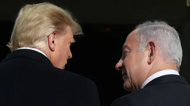 Trump está a la izquierda, de espaldas a la cámara, mirando a la derecha hacia Netanyahu, quien también está de espaldas.