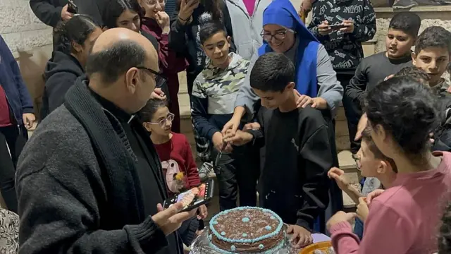 El padre Gabriel y la hermana peruana la María Emperatriz de América ayudan a un niño a cortar su torta de cumpleaños de chocolate