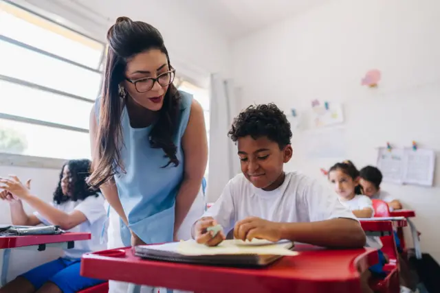 Una profesora ayuda a un chico en el colegio