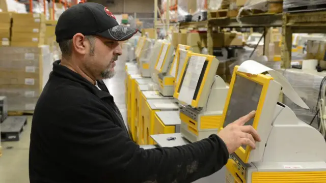 Un técnico realiza una verificación en un quiosco de impresión de fotografías Kodak.