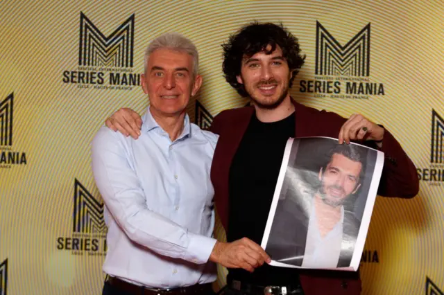 Pier con Pierpaolo Spollon, sosteniendo una foto del actor que lo encarna: Luca Argentero.