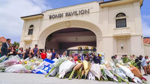 Una creciente exhibición de flores y tributos se ve en un monumento afuera del Pabellón Bondi, en honor a las víctimas de un ataque con tiroteo masivo que mató a 15 personas en Bondi Beach en Sydney, Nueva Gales del Sur, Australia, el 14 de diciembre de 2025.