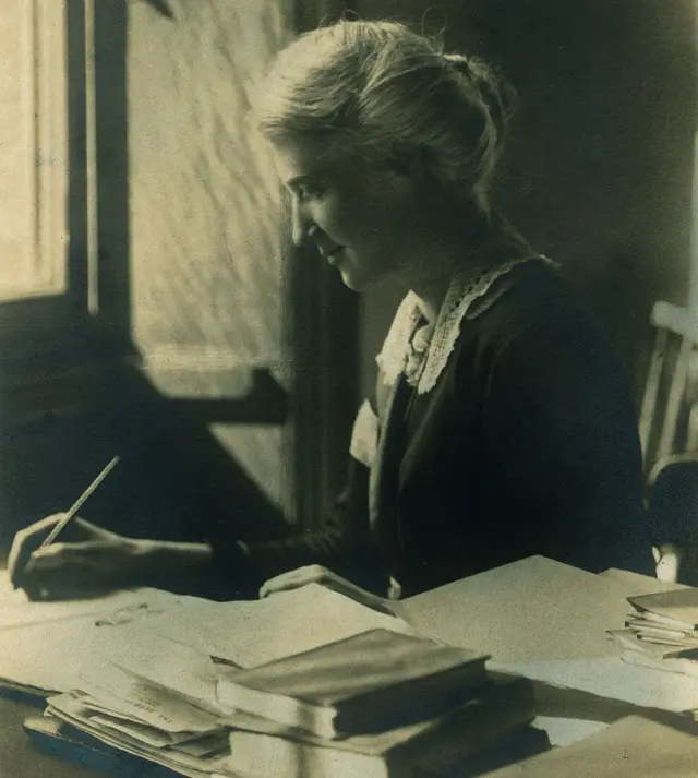 Eglantyne Jebb, escribiendo en un escritorio lleno de papeles y libros