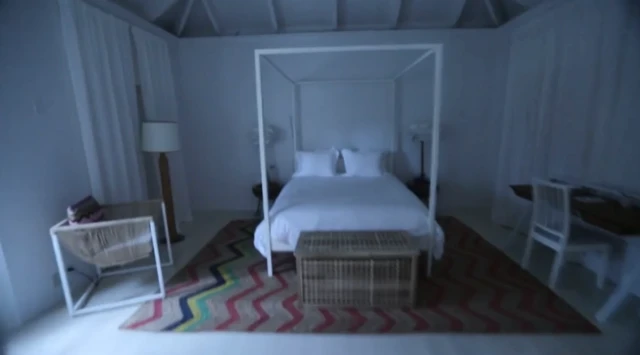 Un dormitorio en la casa de Epstein con una cama con dosel, un sillón y un escritorio.
