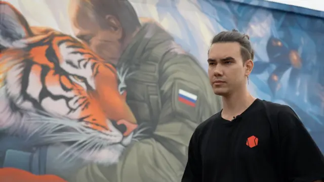 Filipp Dulmachenko, junto al mural que ha pintado con la imagen de Putin abrazado a un tigre siberiano.