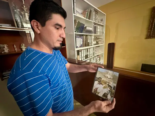 Un hombre católico en Chiclayo muestra una foto de Robert Prevost celebrando misa en su barrio.