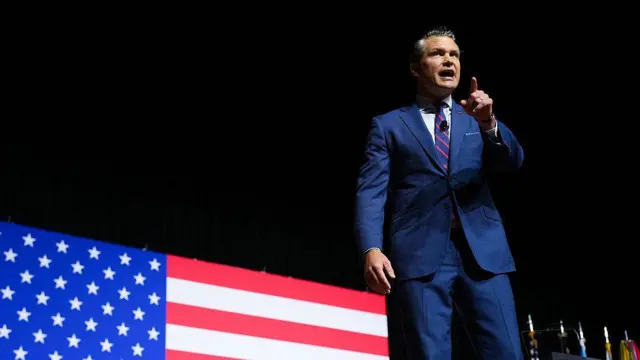 El secretario de Defensa, Pete Hegseth se dirige al público durante un evento, con una gran bandera de Estados Unidos como fondo