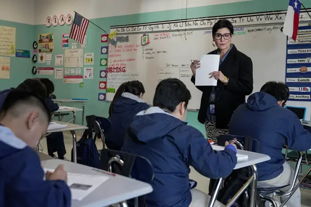 Una maestra y sus alumnos en un salón de clase.