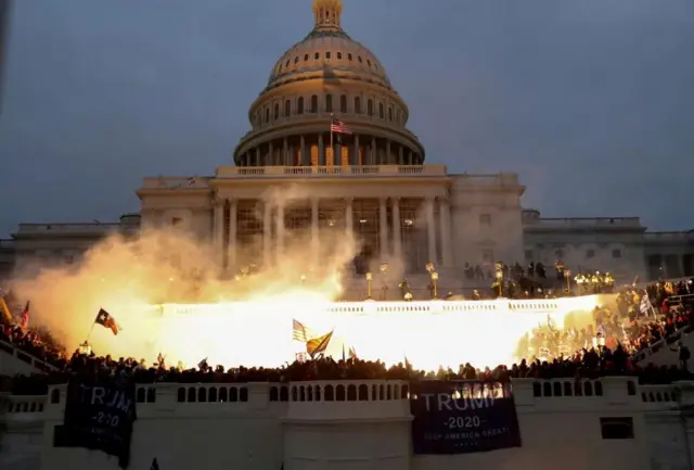 Una explosión causada por el disparo de un policía ilumina el frente del Capitolio en Washington DC, el 6 de enero de 2021  