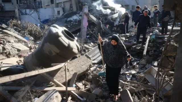 Palestinos caminando entre los escombros tras un ataque de Israel.