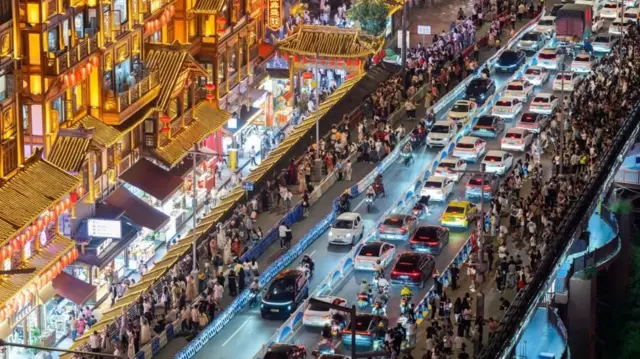 Una toma aérea de noche de la concurrida Chongqing en la que se ven tiendas, vehículos y personas caminando