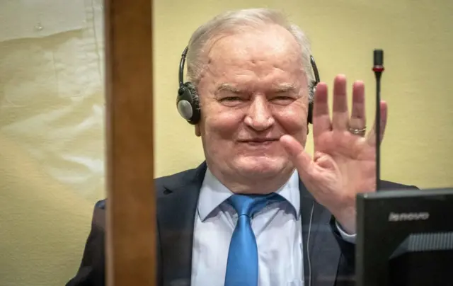 Ratko Mladic saluda sonriente en el juicio que le condenó.