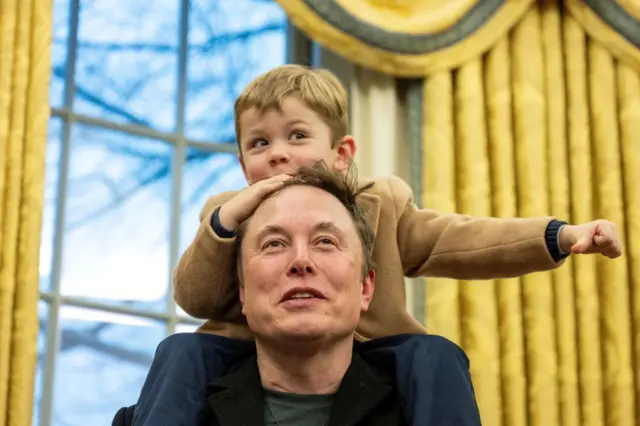 Elon Musk lleva a su hijo X Æ A-Xii sobre sus hombros mientras habla en el Despacho Oval.