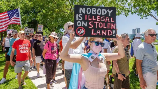Manifestantes y una joven en primer plano con una pancarta que dice: