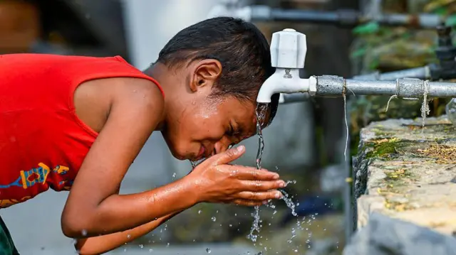 Un niño calma su sed con agua del grifo de un tanque durante una ola de calor abrasadora el 12 de junio de 2025 en Nueva Delhi, India.