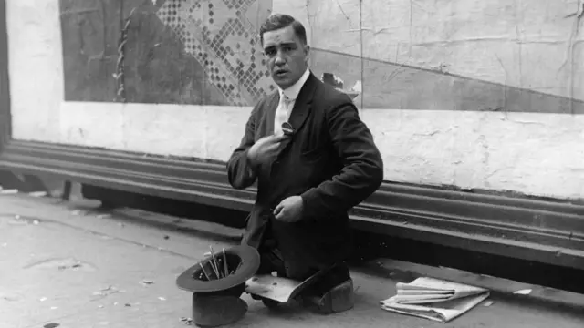Un hombre sin piernas vende lápices en las calles en 1910.