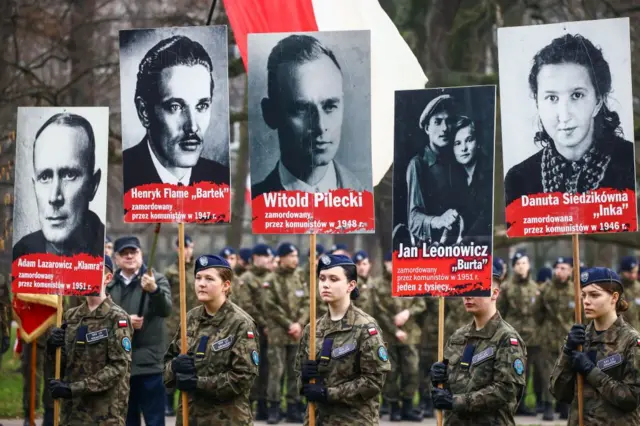 Mujeres uniformadas sostienen pancartas con las fotos de Witold Pilecki y otros mártires anticomunistas en la llamada marcha de los 