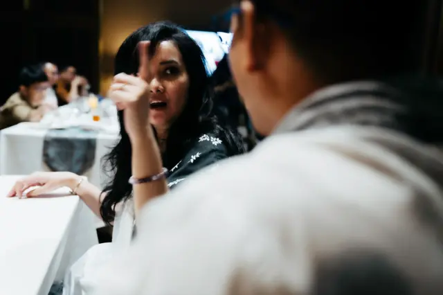 Una mujer discute con un hombre en una mesa de una reunión familiar