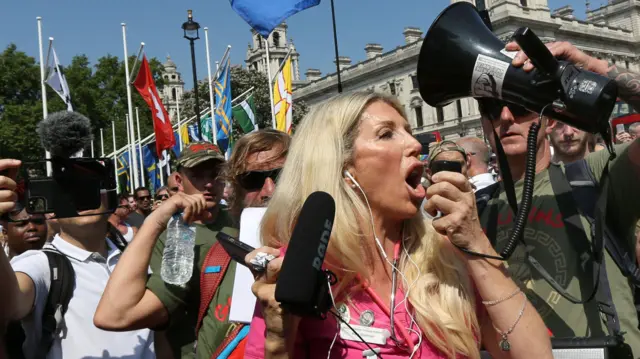 Kate Shemirani hablando por un altoparlante, durante una protesta contra el confinamiento por la pandemia de covid en 2021